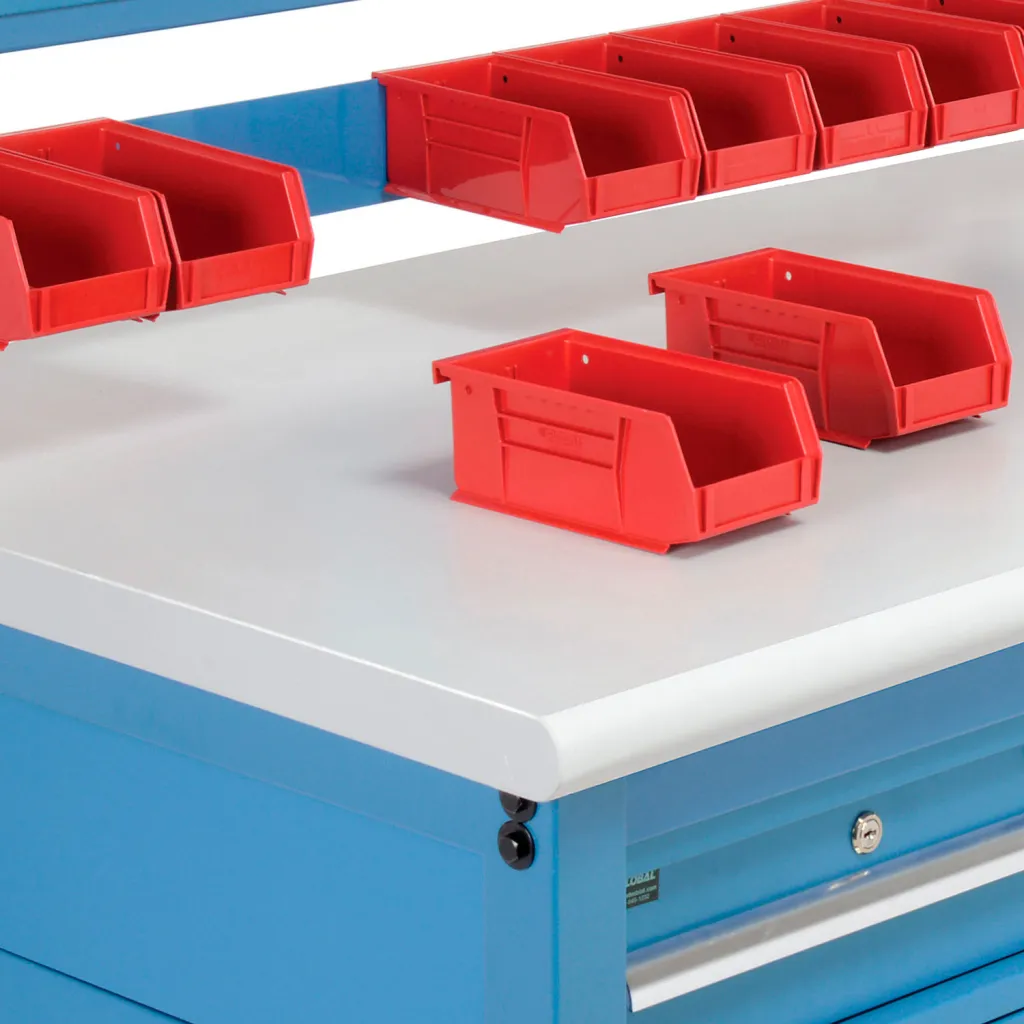A close-up of a workbench with red bins and a white top