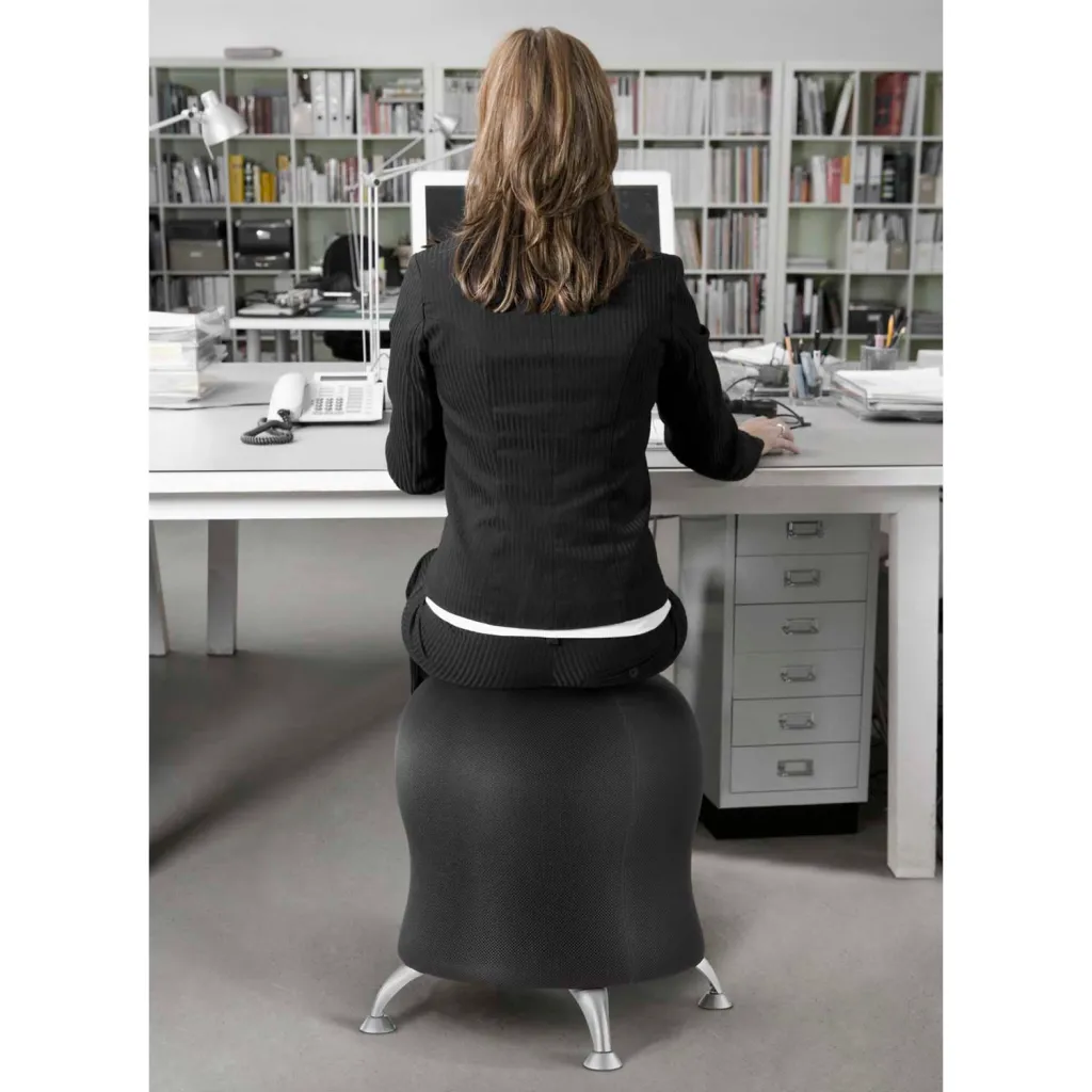 A black, egg-shaped chair with a silver base, being used by a woman in business attire at a desk.