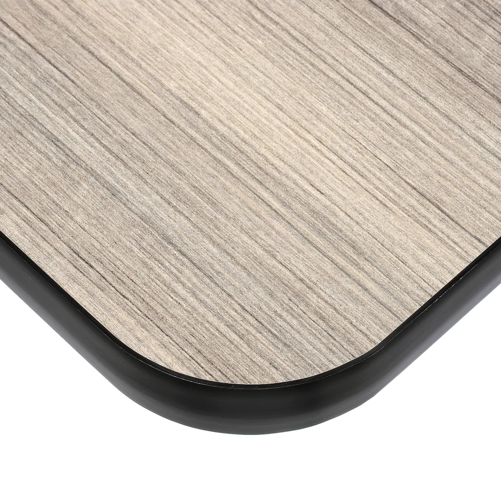 Close-up of table corner with gray wood grain top and black edge