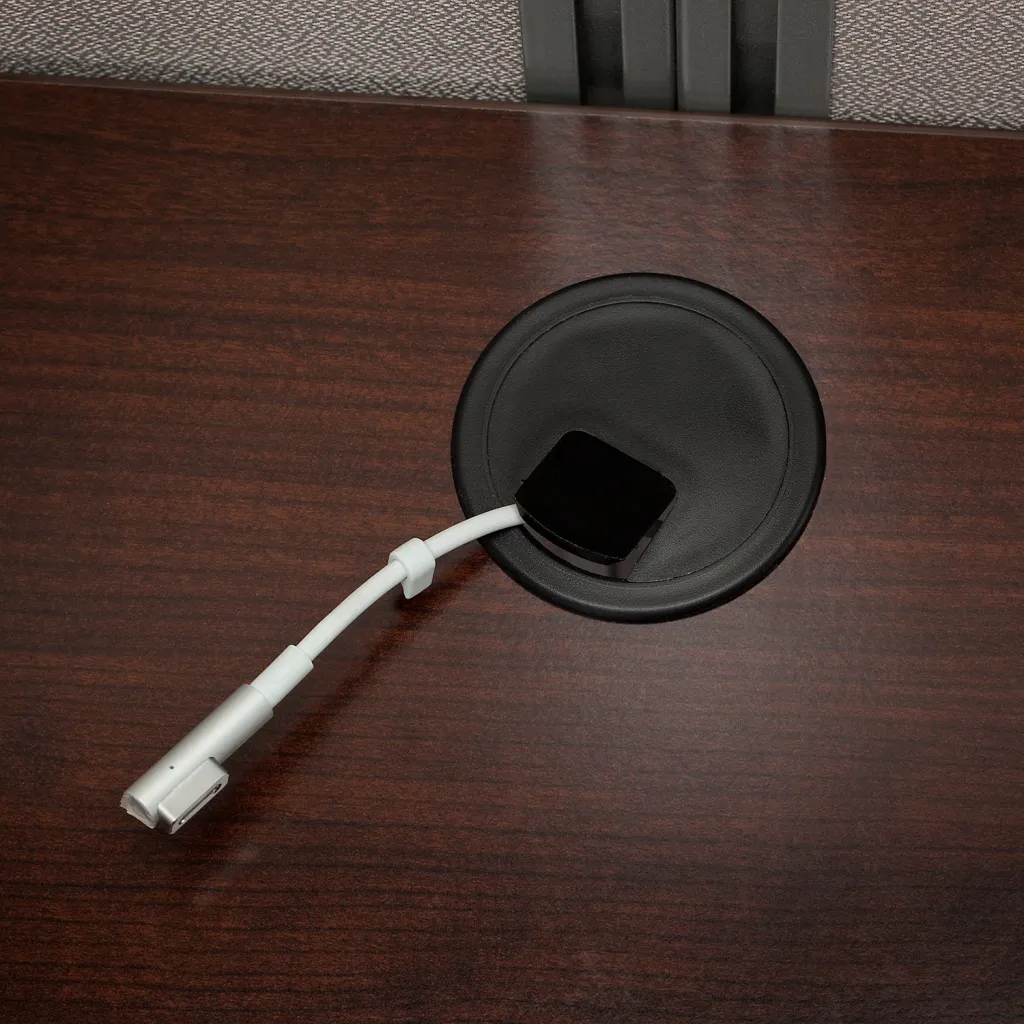 Close-up of a dark wood desk with a built-in power outlet