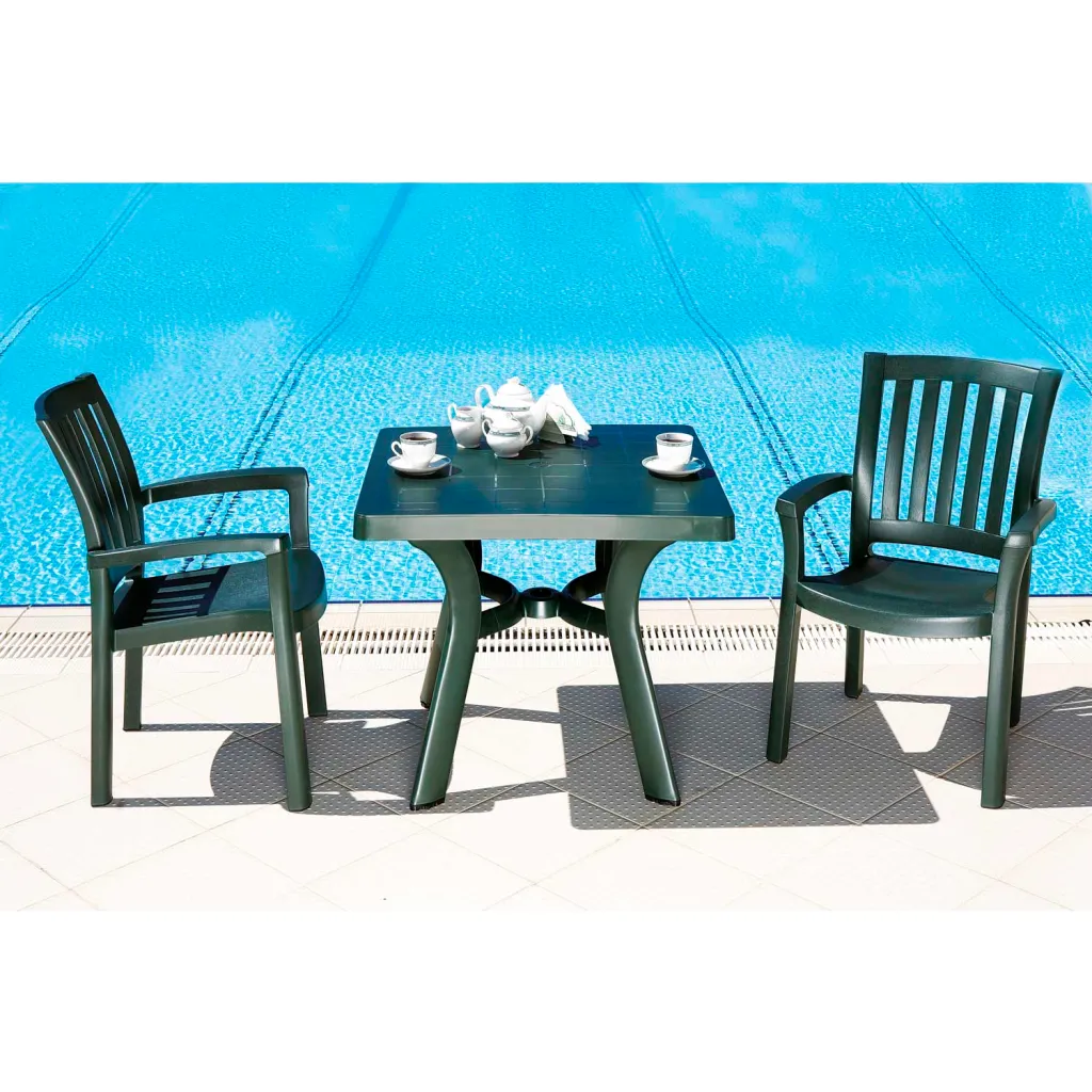 Two black plastic chairs and rectangular table by pool