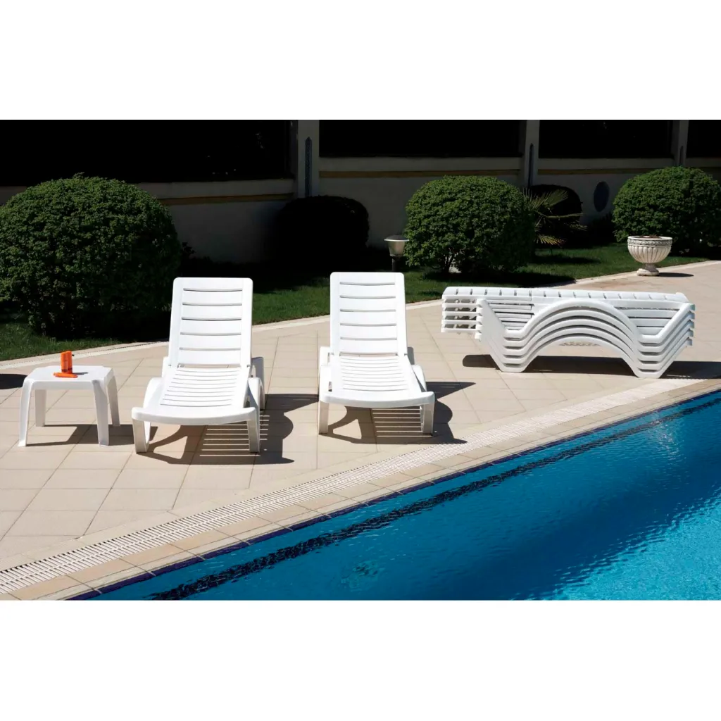 White plastic lounge chairs and table by a pool