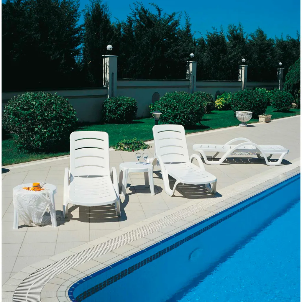 Two white lounge chairs by pool