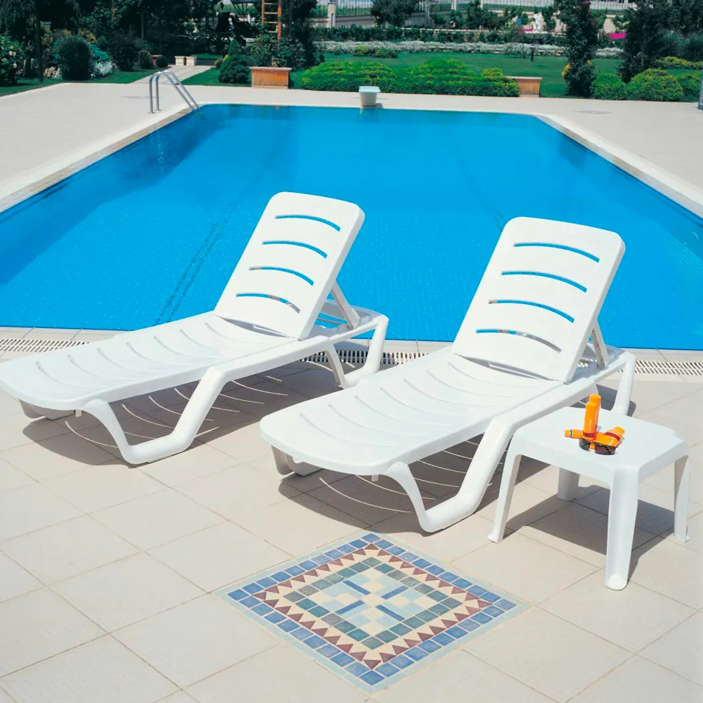 White plastic lounge chairs and table by a pool