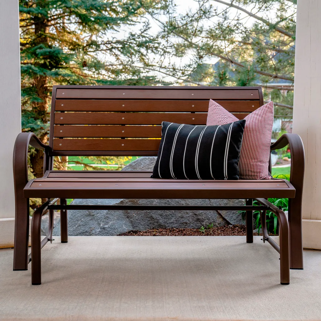 Brown metal bench with slatted back and seat and pillows