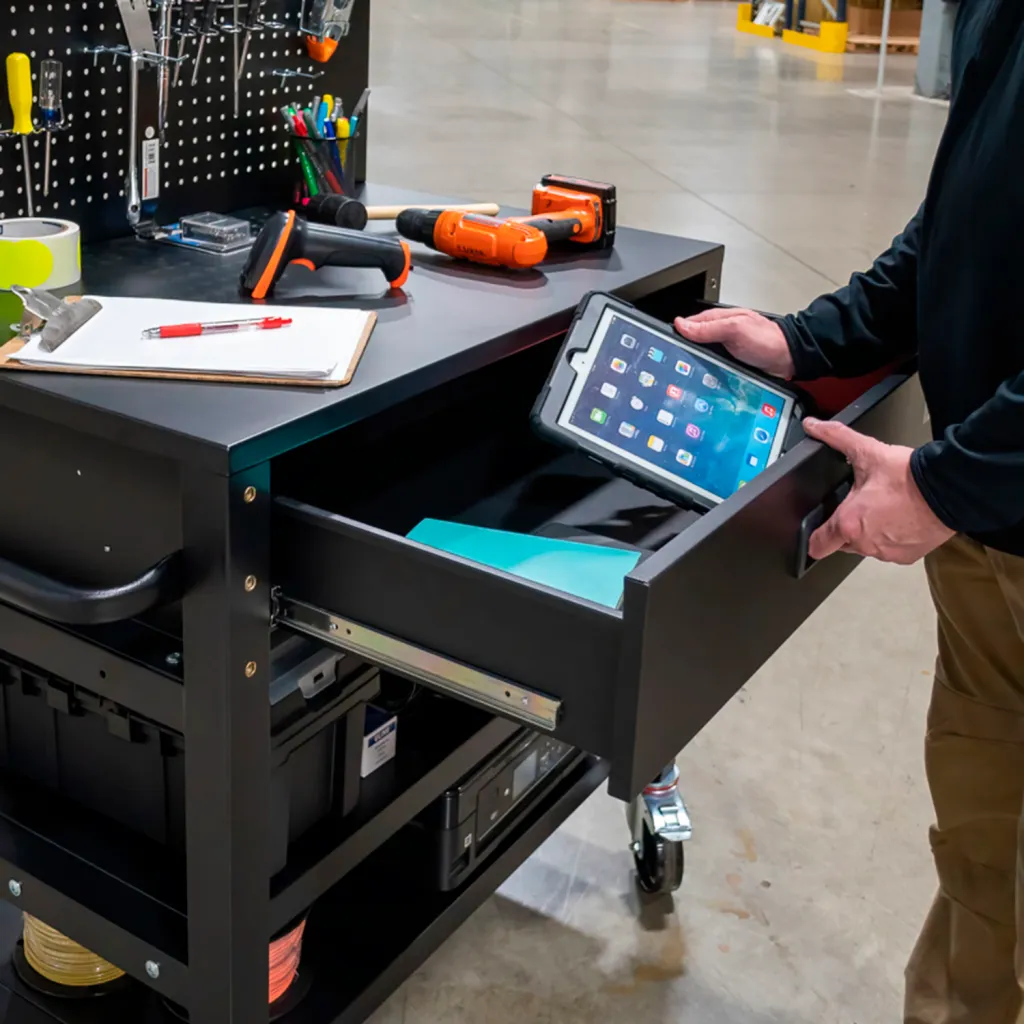 Person opening drawer of black metal tool cart with tools and tablet inside