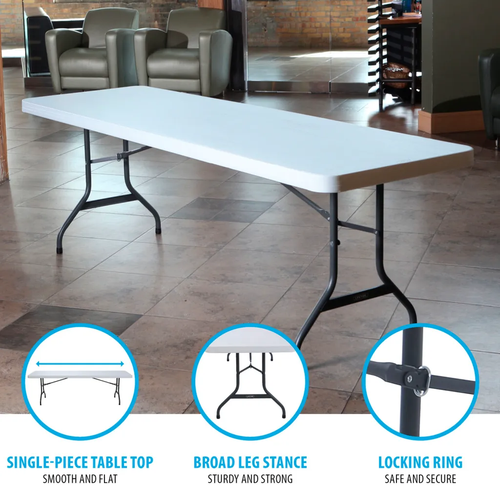 A white folding table with black metal legs in a room with chairs and a brick wall.