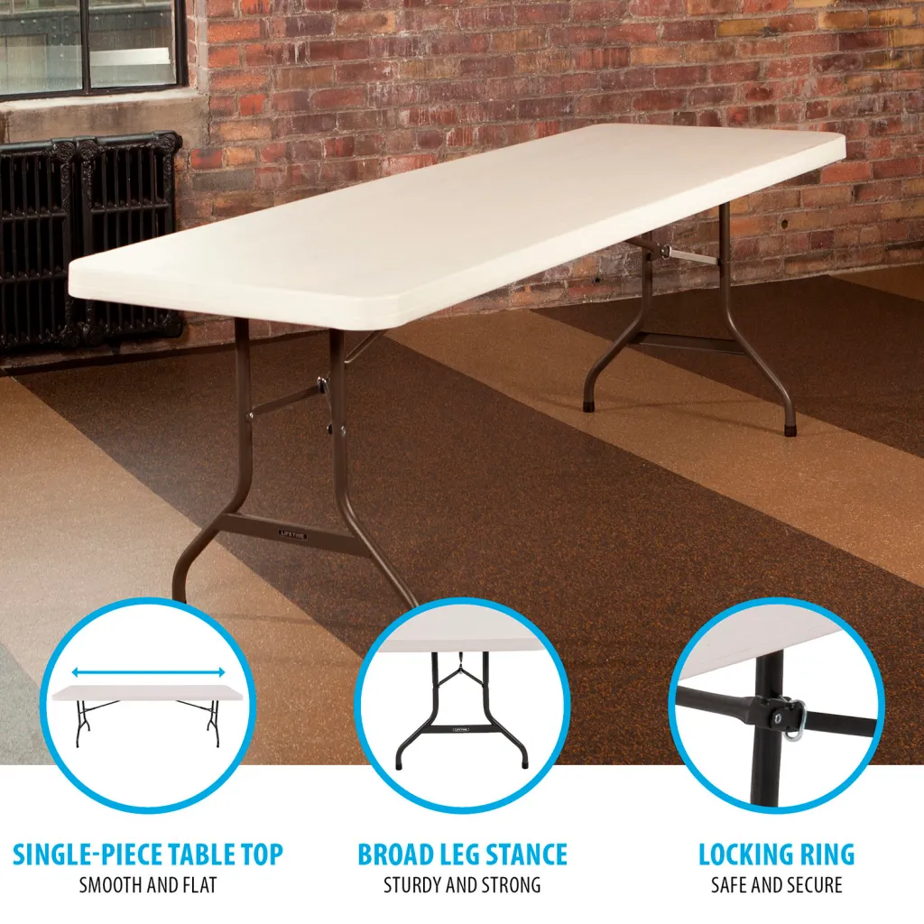 A white folding table with black metal legs set up in a room with a brick wall.