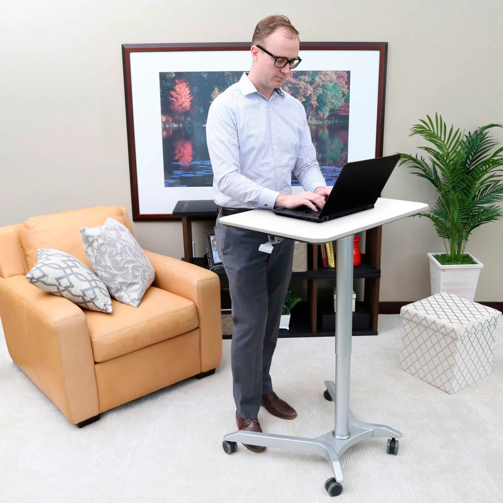 A man using the desk as a standing desk with his laptop.