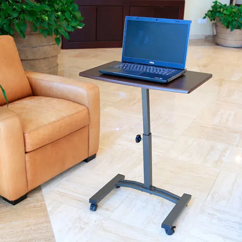 A rolling laptop stand with a laptop on it, next to a chair